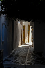 Narrow alley with tunnel and with whitewashed walls and stone pavement leading to a courtyard in the Greek Islands, Greece