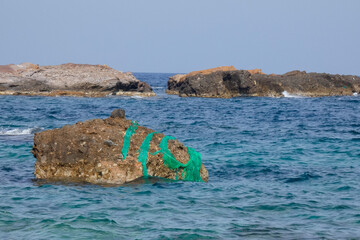 Fishing net abandoned on rock in the ocean polluting the seawater