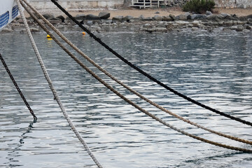 Thick mooring ropes securing a crane barge in the harbor