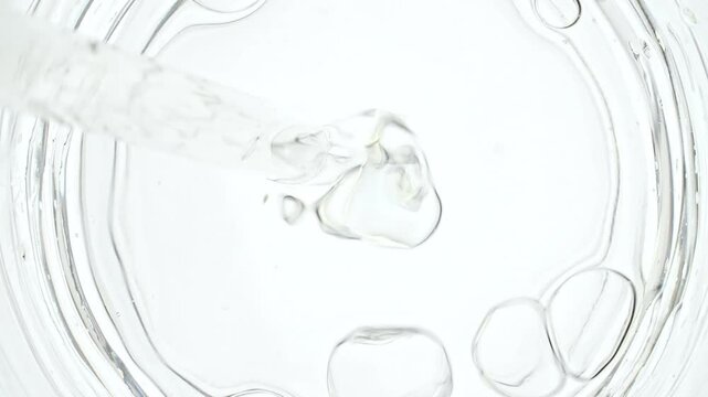 Transparent air Bubbles come out from lab pipet and bursting on the surface of clear fluid in Petri dish. The medicine concept, health care, treatment. Macro Shot of Natural Organic Cosmetics. 4k
