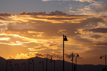 Obraz premium Street lamps silhouetted against a vibrant sunset sky