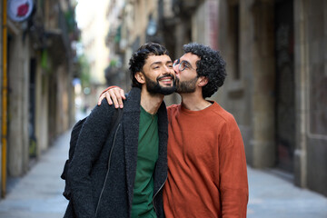 Gay couple kissing on cheek while walking down street