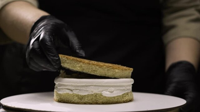 step by step process of making benta cake with banana filling. close up of pastry chef carefully placing second cake layer on caramel filling. step ten