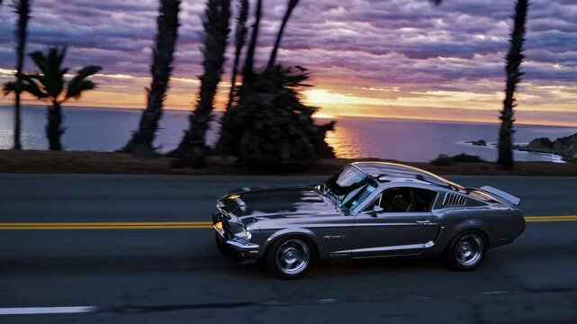 A vintage car speeds along a coastal road at sunset, captured in a dynamic side angle. The video style evokes a sense of nostalgia and adventure.