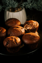 Warm chocolate muffins sitting on a black plate with steam rising in a cozy setting