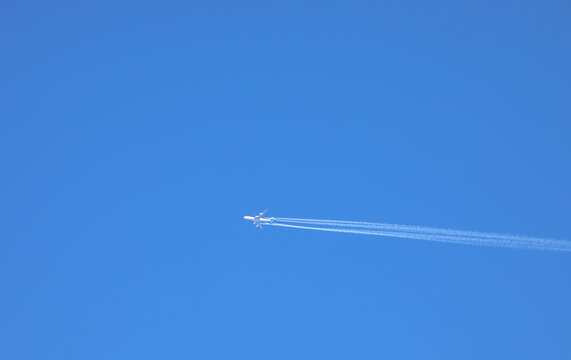 airliner flying high in blue sky leaving white water vapor trail ideal as background for travel