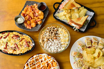 A table with a variety of food items including sandwiches, chips, and pizza