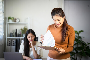 Business team of two executives working together using laptop in office. Happy young business woman manager showing project presentation to mature woman client, investor or partner at work meeting.