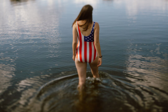 Woman in patriotic swimsuit wading into Sylvan Lake, SD.