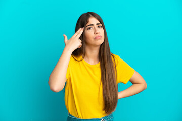 Fototapeta premium Young caucasian woman isolated on blue background with problems making suicide gesture
