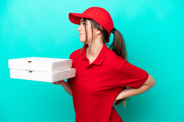 Pizza delivery woman with work uniform picking up pizza boxes isolated on blue background suffering...