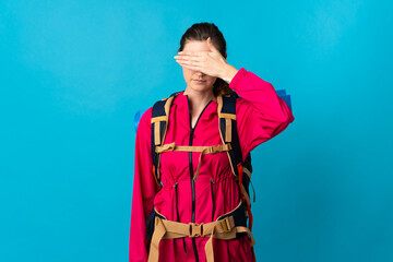 Young mountaineer woman over isolated blue background covering eyes by hands. Do not want to see something