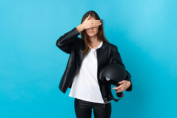 Young Ireland woman holding a motorcycle helmet isolated on blue background covering eyes by hands....