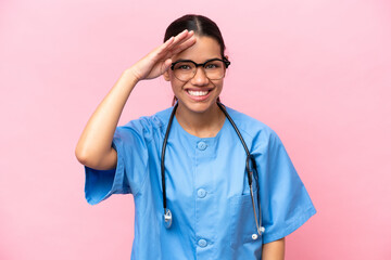 Young nurse Colombian woman isolated on pink background looking far away with hand to look something