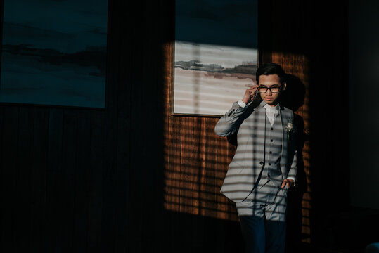 A young man holding an eyeglass while looking through a window
