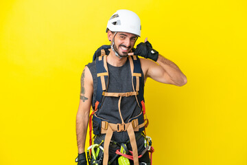Fototapeta premium Young caucasian rock climber man isolated on yellow background making phone gesture. Call me back sign