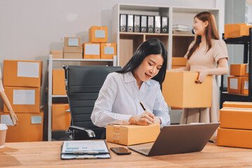 Asian SME business women use laptop computer checking customer order online shipping boxes at home....