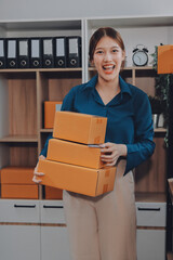 Asian SME business women use laptop computer checking customer order online shipping boxes at home....