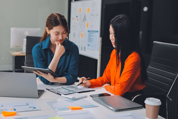 Entrepreneur Asian businessman and businesswoman discussing new business project in tablet in modern Meeting In Modern Office, Asian business casual concept.