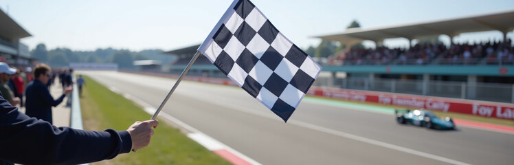 A Checkered Flag Is Waved From A Gantry Above The Track With A Racing Circuit Visible Behind It.