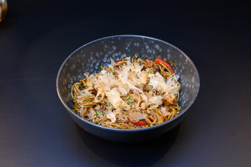 A bowl of noodles with a lot of sauce and garnish