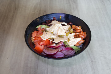 A bowl of food with a variety of ingredients including tomatoes, onions