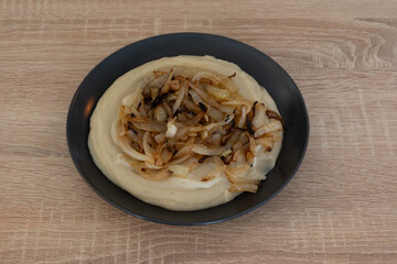A plate of food with onions and potatoes on a wooden table