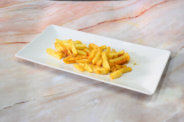 A plate of french fries sits on a marble countertop