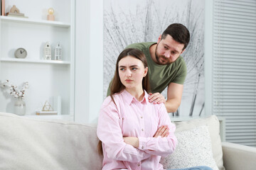 Man comforting his resentful girlfriend at home. . Relationship problem