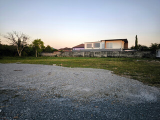 Obraz premium Empty Gravel Lot Near Residential Homes at Sunset
