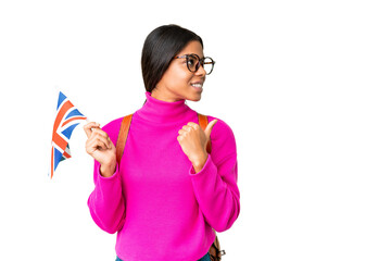 Young African American woman holding an United Kingdom flag over isolated chroma key background pointing to the side to present a product