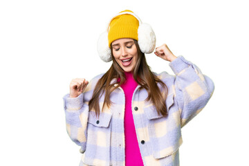 Young woman wearing winter muffs over isolated chroma key background celebrating a victory