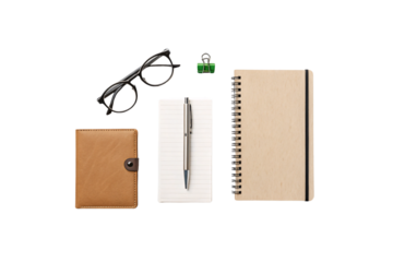 A brown leather notebook, black-framed glasses, a silver pen, a green binder clip, and a spiral-bound journal, neatly arranged for a stylish workspace, isolated on a transparent background
