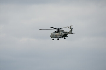 British Royal Navy Agusta-Westland Merlin HM.2 AW101 helicopter hovering and flying low under white...