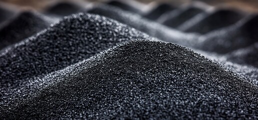 Close-up piles of black granulated material, indoors with blurred background and macro focus