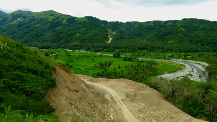 Dirt road in tropical mountains. Dirt road on a hillside. The road passes through a picturesque valley of a tropical island.