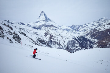 Skier descending a slope with the majestic Matterhorn in the background, creating a stunning alpine scene