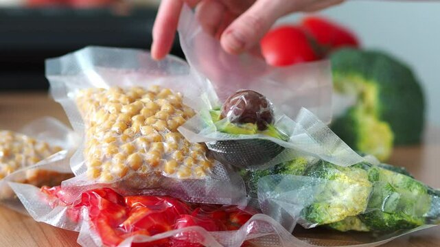 Background in the kitchen with vacuum bags with vegetables lying on the table. Convenient storage of products. Sealed products broccoli, tomatoes, peppers, champignons, legumes.