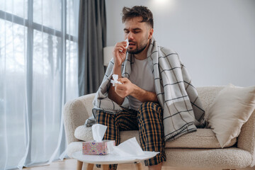 Nasal spray for nose. Sick man is feeling bad at home