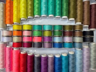 Colorful sewing thread spools and bobbins in a box. Lay flat view.