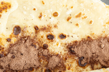 A close-up of a crepe sprinkled with cocoa powder.