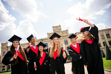 Joyful graduates celebrating their achievement on a sunny summer day in an urban campus setting