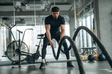 Endurance cross fit with knots. Man is in the modern gym