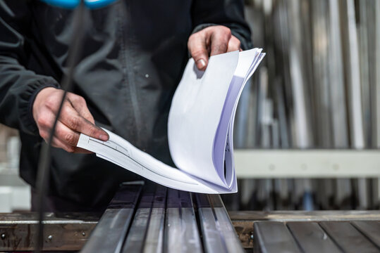 Dans un atelier de m&eacute;tallerie, le technicien est en train de v&eacute;rifier les plans pour continuer son projet. Gros plan sur la lecture des plans donn&eacute; par le bureau d'&eacute;tude.