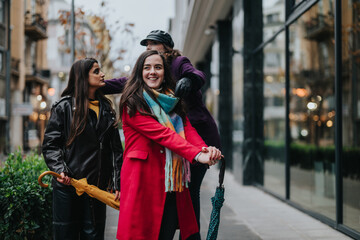 Obraz premium Three women dressed stylishly, walking in an urban setting, sharing joyful moments and enjoying their time together outdoors amidst city architecture and autumn vibes.