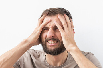 Man holding his head with both hands, showing visible discomfort, possibly suffering from a severe...