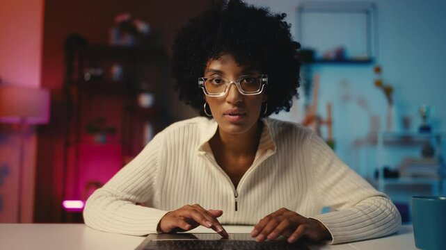African American woman journalist types on her laptop, working remotely, pov