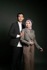 Elegant couple posing in stylish formal attire against a dark studio background