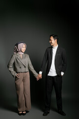 Stylish couple holding hands and looking at each other with love