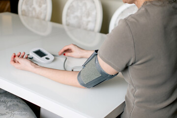 A device that measures blood pressure and is placed near a person's arm. The device has a screen...
